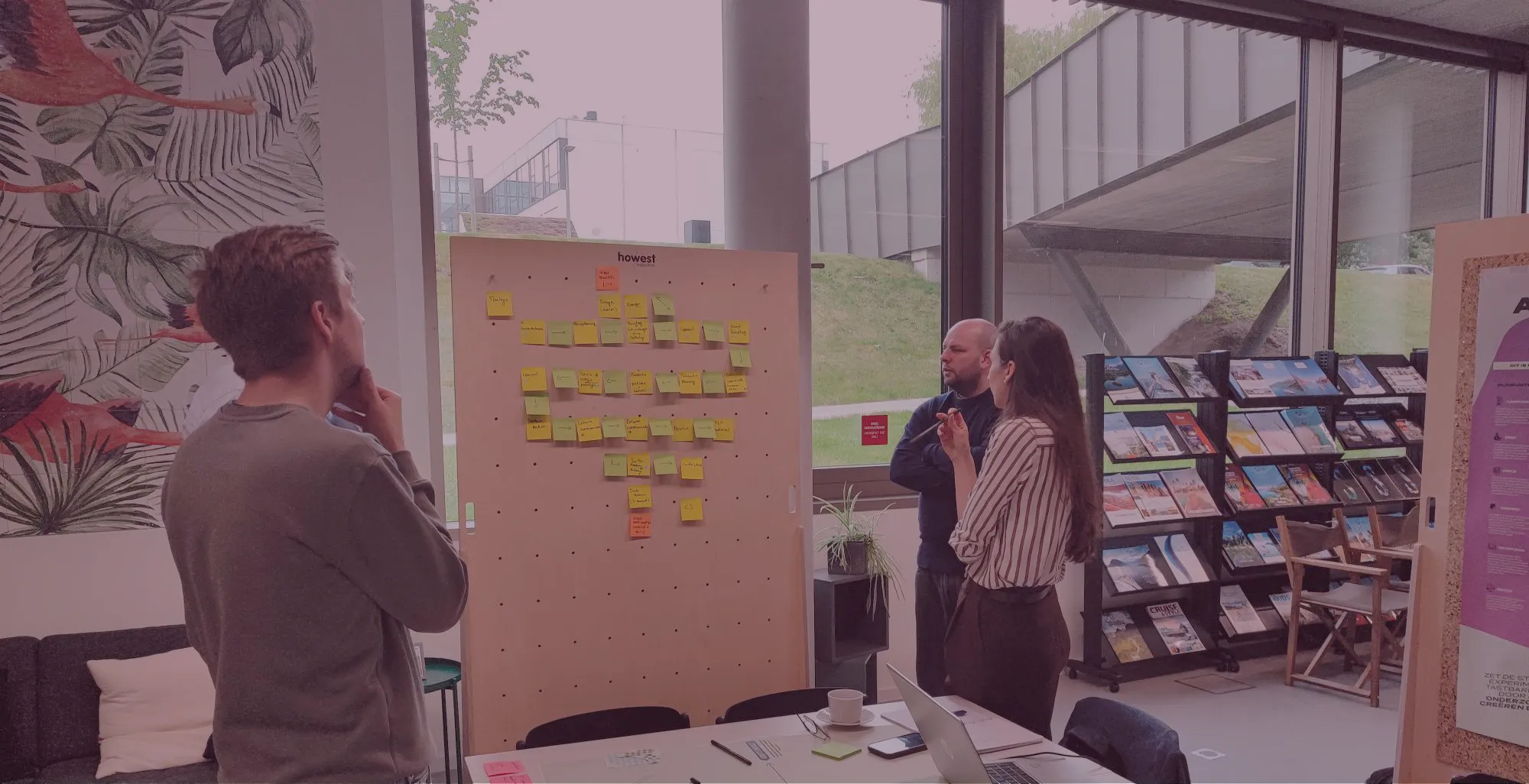 Deelnemers bespreken een workflow met post-its op een houten bord tijdens een workshop
